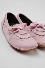 Load image into Gallery viewer, A pair of light pink slip-on shoes with scalloped trim, ribbon bows, and lace-up details, shown on a light gray background.