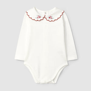 White baby bodysuit with floral collar on a light gray background