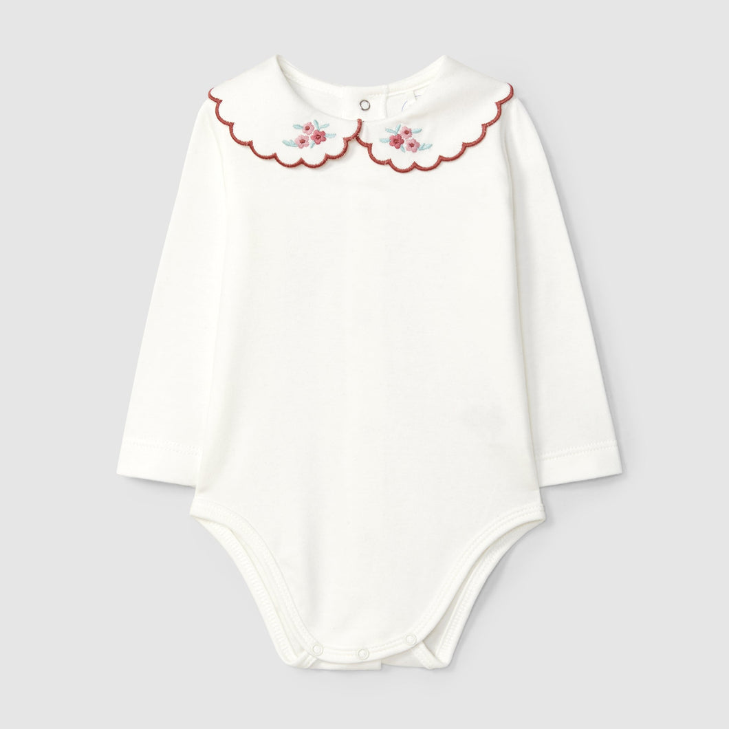 White baby bodysuit with floral collar on a light gray background