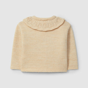 Beige knitted cardigan with a ruffled collar on a light gray background