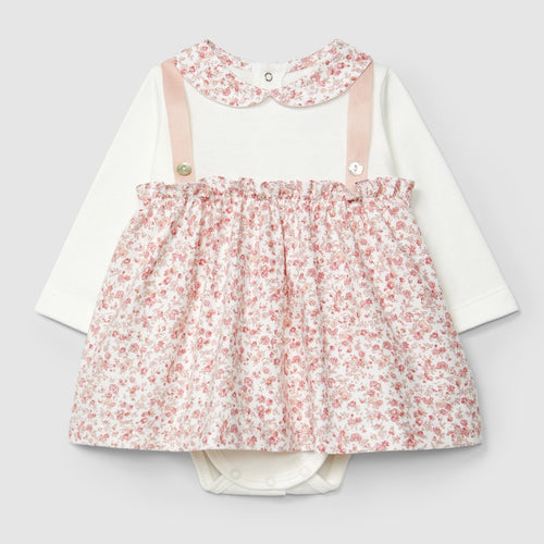 Children's outfit with floral dress over a white shirt on a light gray background