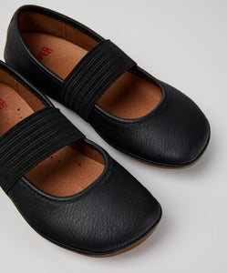 Black shoes with elastic straps on a light gray background