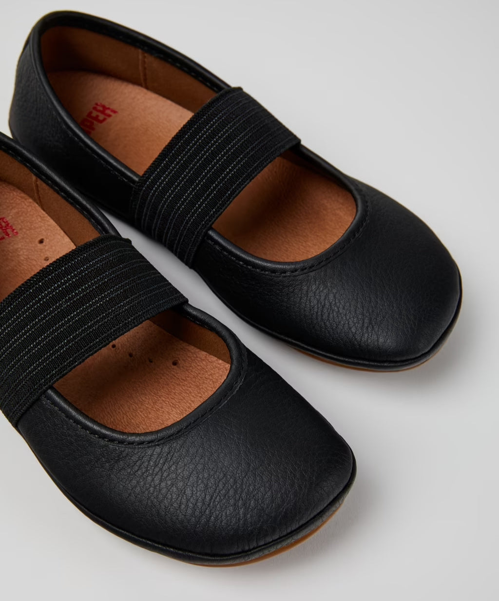 Black shoes with elastic straps on a light gray background
