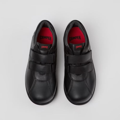 Pair of black shoes with red soles on a light gray background