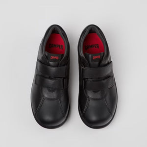 Pair of black shoes with red soles on a light gray background