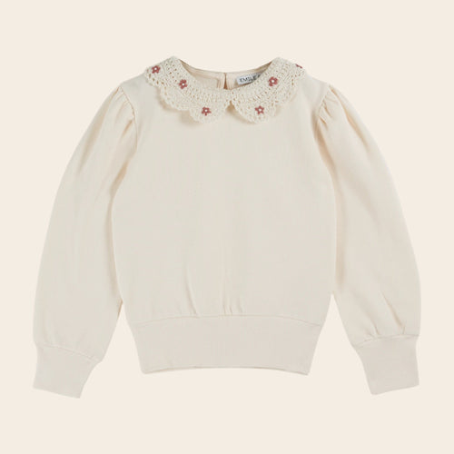 White sweater with floral lace collar on a beige background