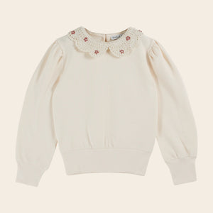 White sweater with floral lace collar on a beige background