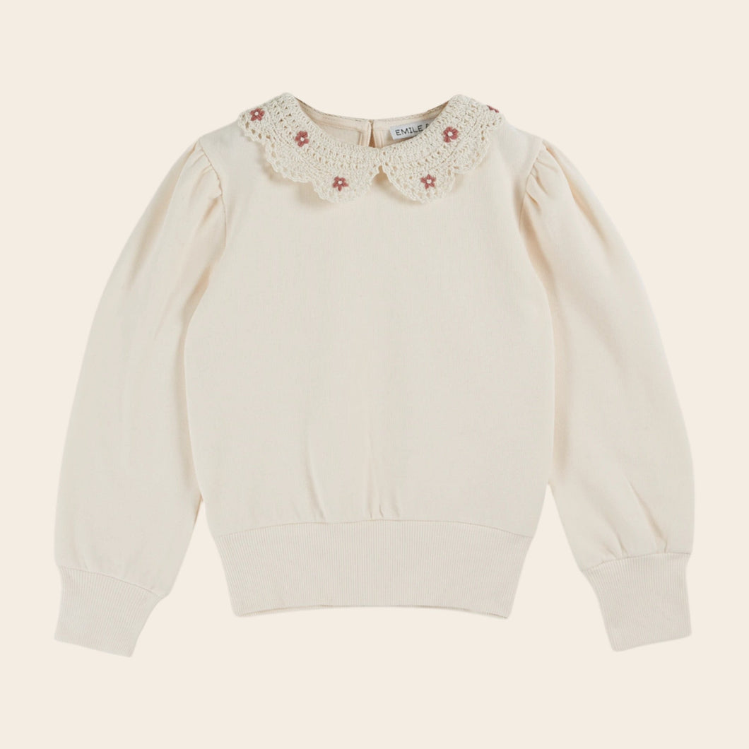 White sweater with floral lace collar on a beige background