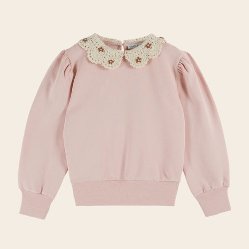 Pink sweater with a floral lace collar on a beige background