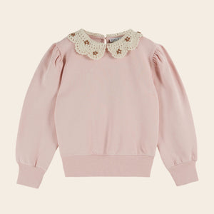 Pink sweater with a floral lace collar on a beige background
