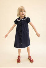 將圖片載入圖庫檢視器 Young girl wearing a navy dress with white trim on a light pink background