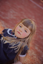 將圖片載入圖庫檢視器 Young girl with blonde hair and a dark top on a textured surface