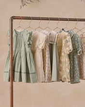 Load image into Gallery viewer, Noralee Daisy Summer Ditsy Dress hanging on a rack with floral print and lightweight fabric, perfect for warm weather wear.
