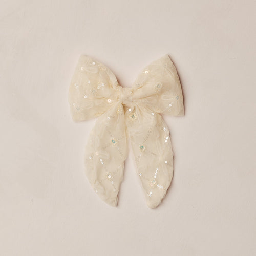 White bow with polka dots on a beige background