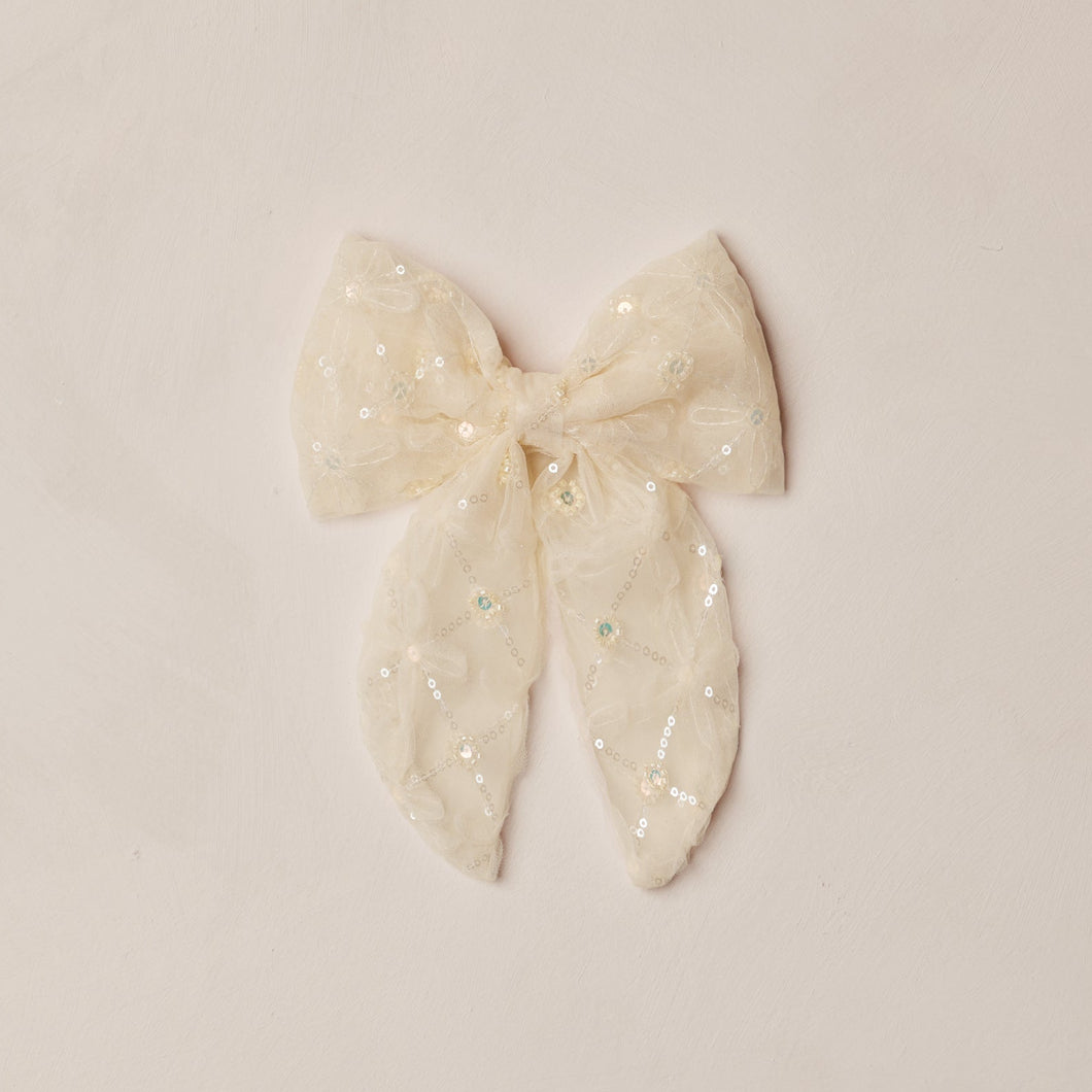 White bow with polka dots on a beige background