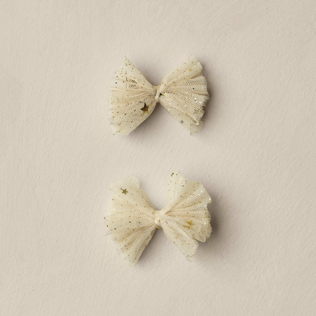 Pair of beige bow-shaped earrings on a beige background