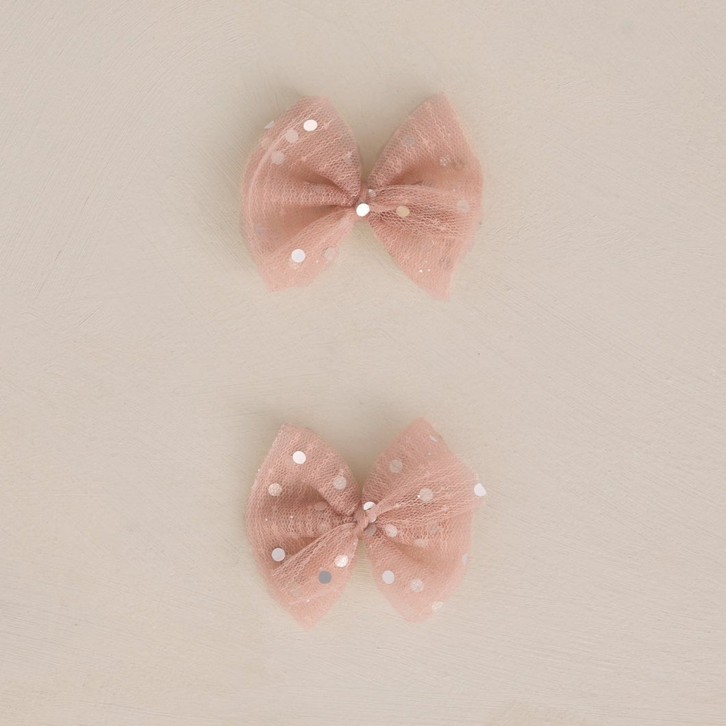 Two pink decorative bows on a beige background