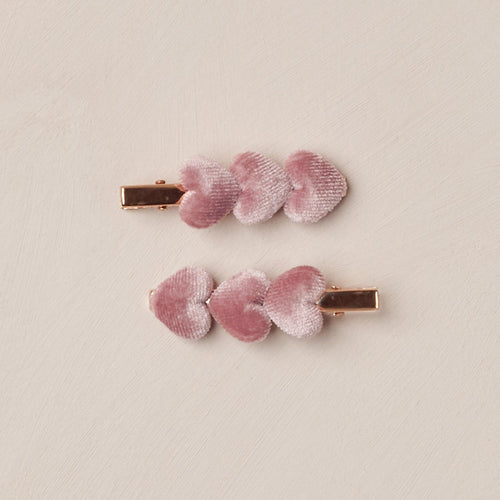 Two pink hair clips with floral design on a beige background