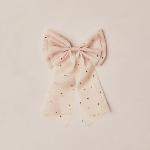 Pink bow with black polka dots on a beige background