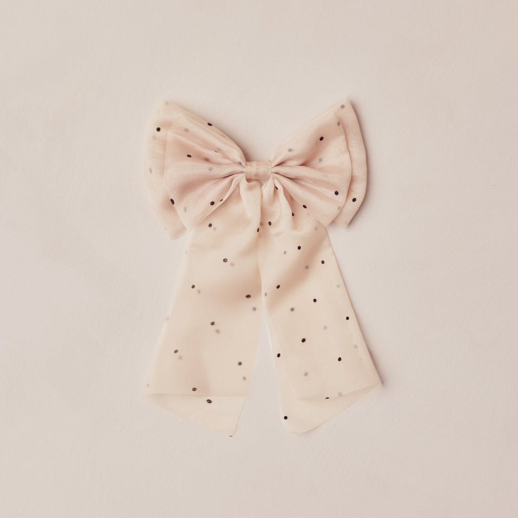 Pink bow with black polka dots on a beige background