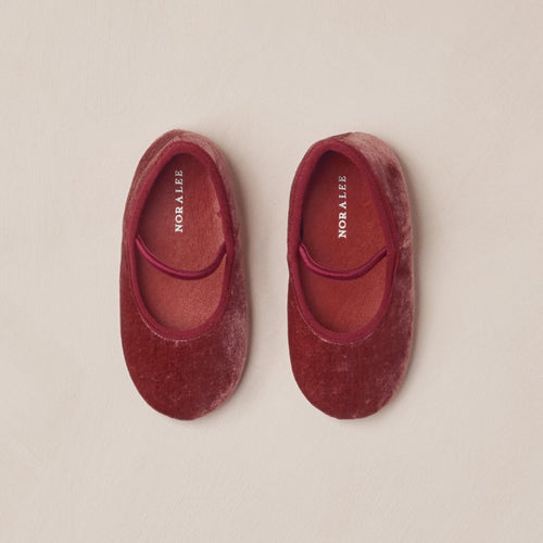 Pair of red velvet slippers on a beige background