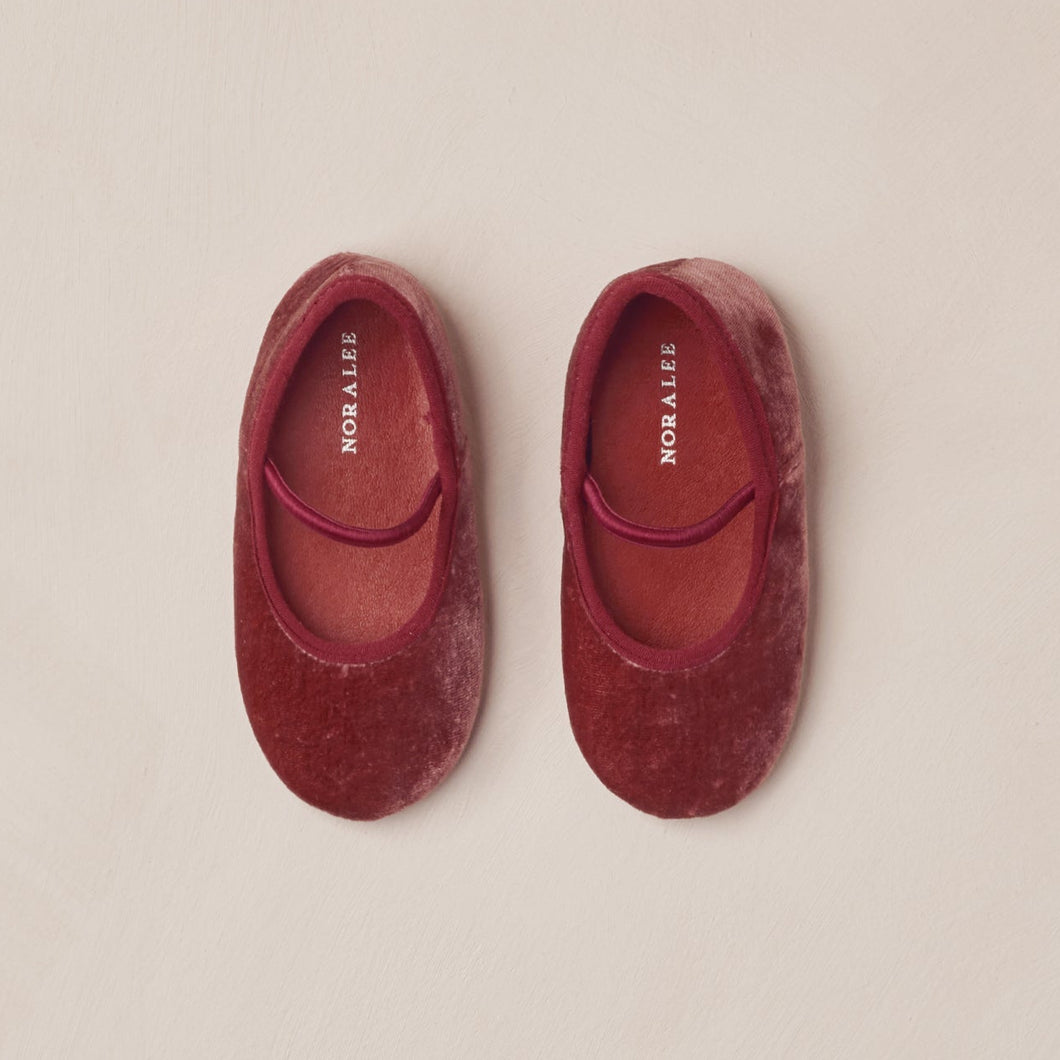 Pair of red velvet slippers on a beige background