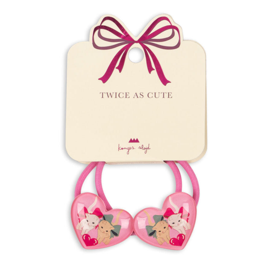 Pink heart-shaped hair ties with cartoon characters on a beige card with a pink bow, branded 'Lavish Angel'.