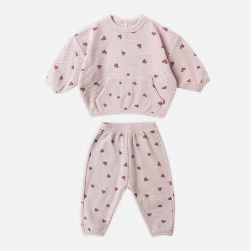 Pink children's sweatshirt and pants set with heart patterns on a white background