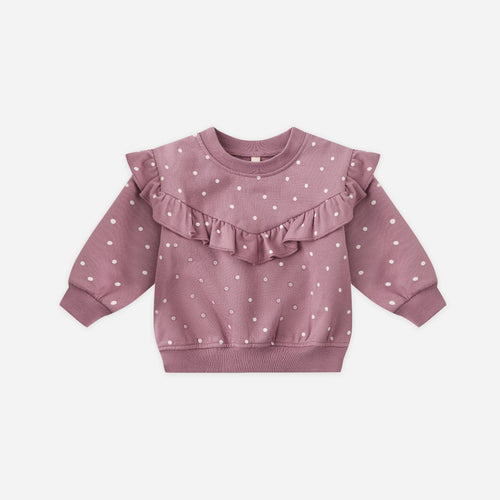 Pink baby sweater with ruffled details on a light pink background