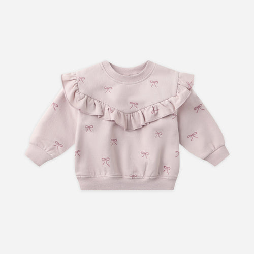 Pink baby sweater with ruffled details on a white background