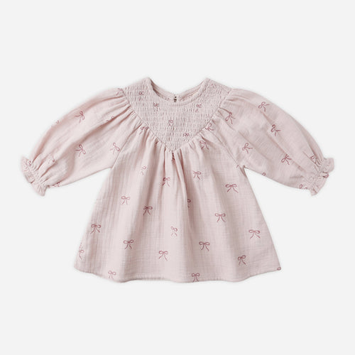 Pink baby dress with bow pattern on a white background