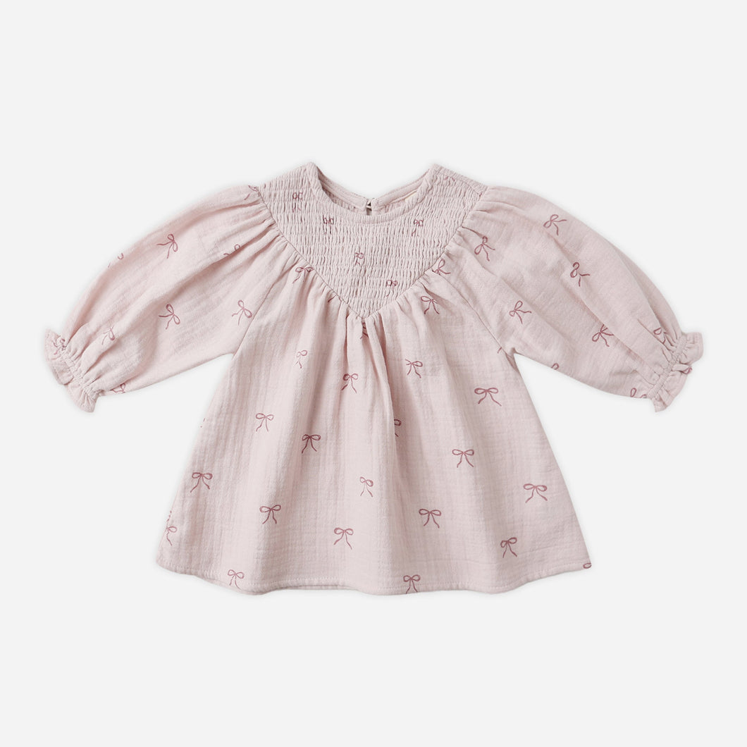 Pink baby dress with bow pattern on a white background