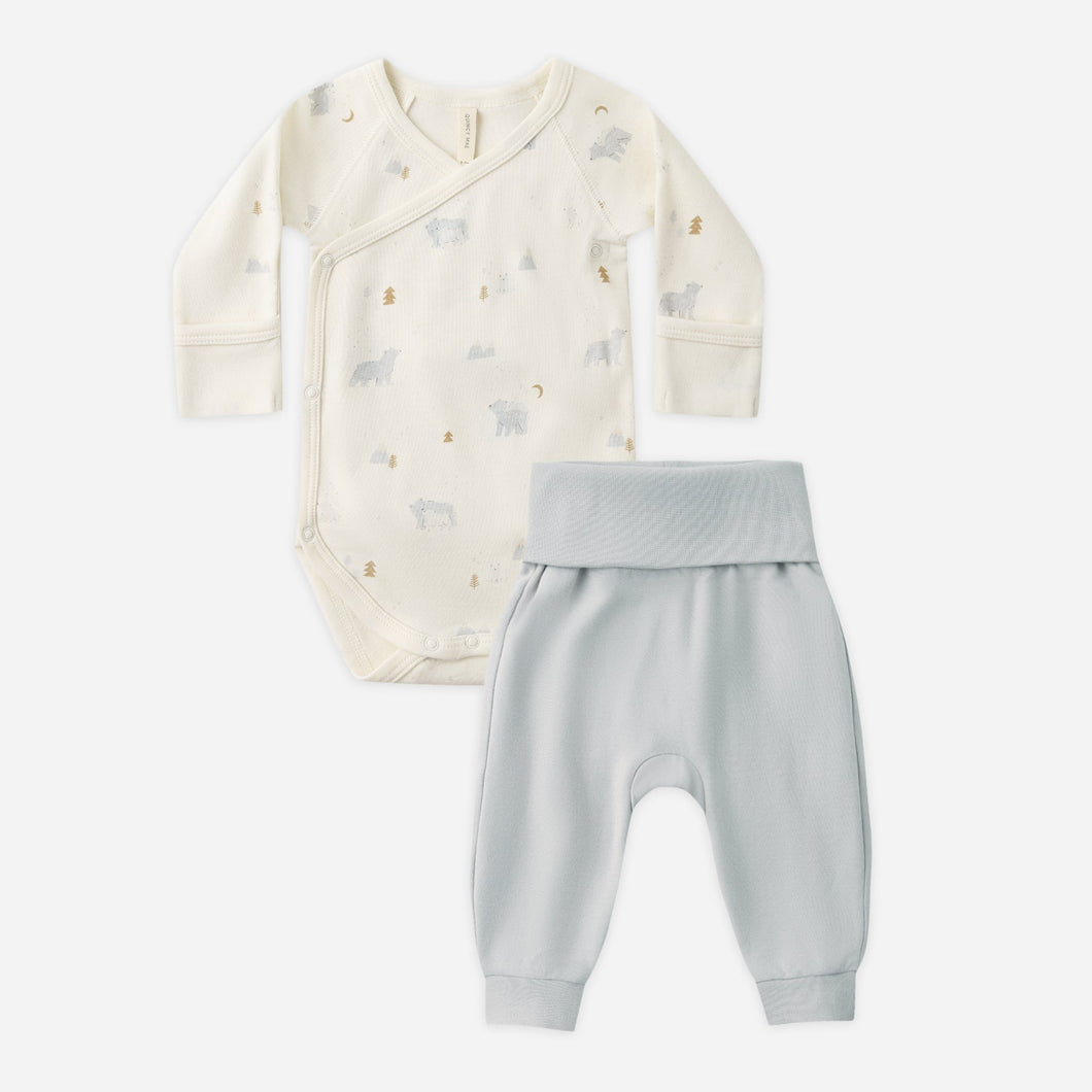 Baby outfit with a white hoodie and gray pants on a light beige background