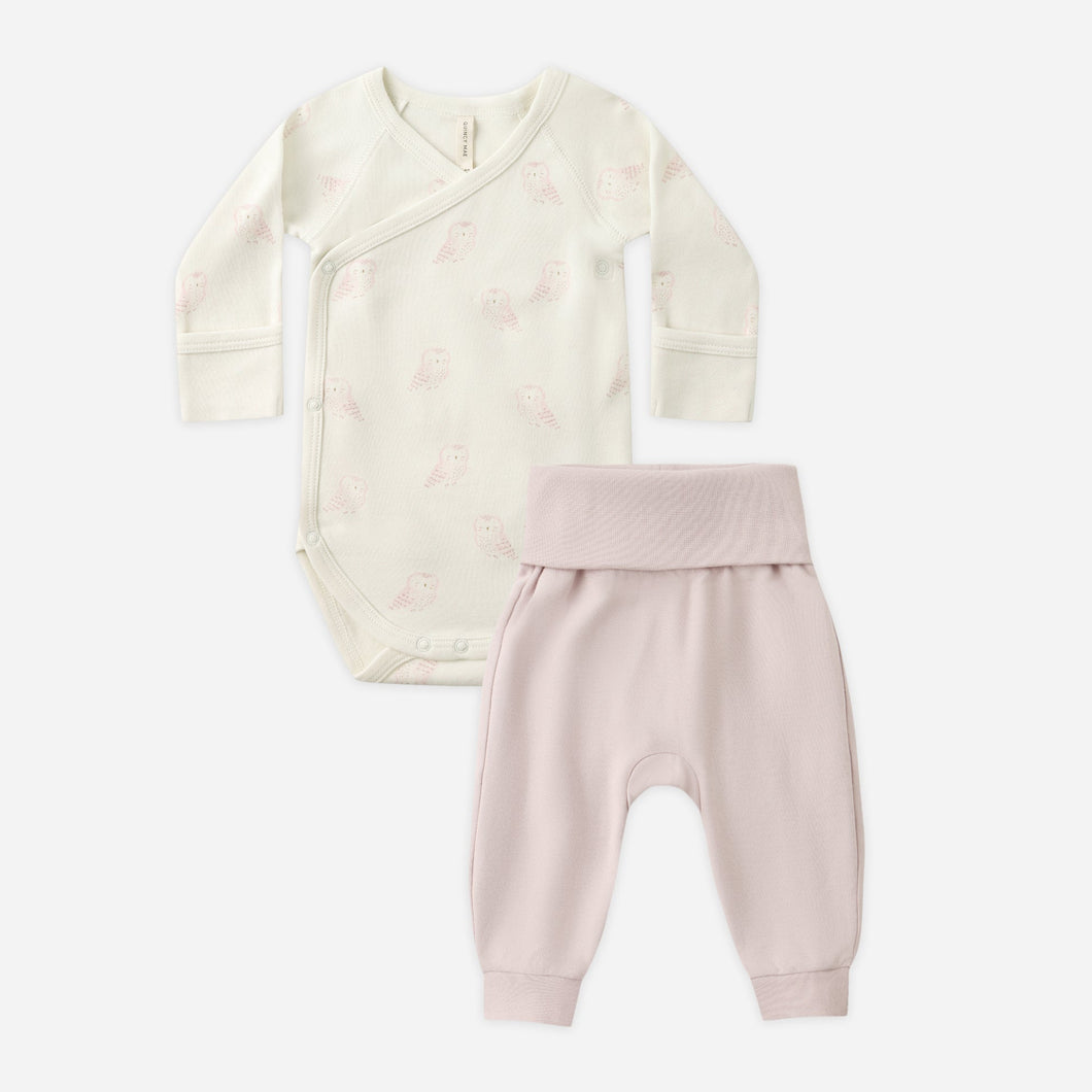 Baby outfit set with cream onesie and pink pants on a white background