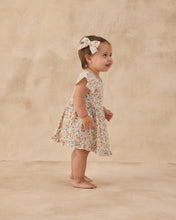 Load image into Gallery viewer, Rylee+Cru Bow Flower Field headband with fabric bow and floral pattern, styled on a neutral backdrop.