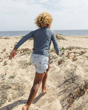 Load image into Gallery viewer, Baby and toddler navy long sleeve rashguard by Rylee+Cru, shown worn by a child at the beach with ocean in the background.
