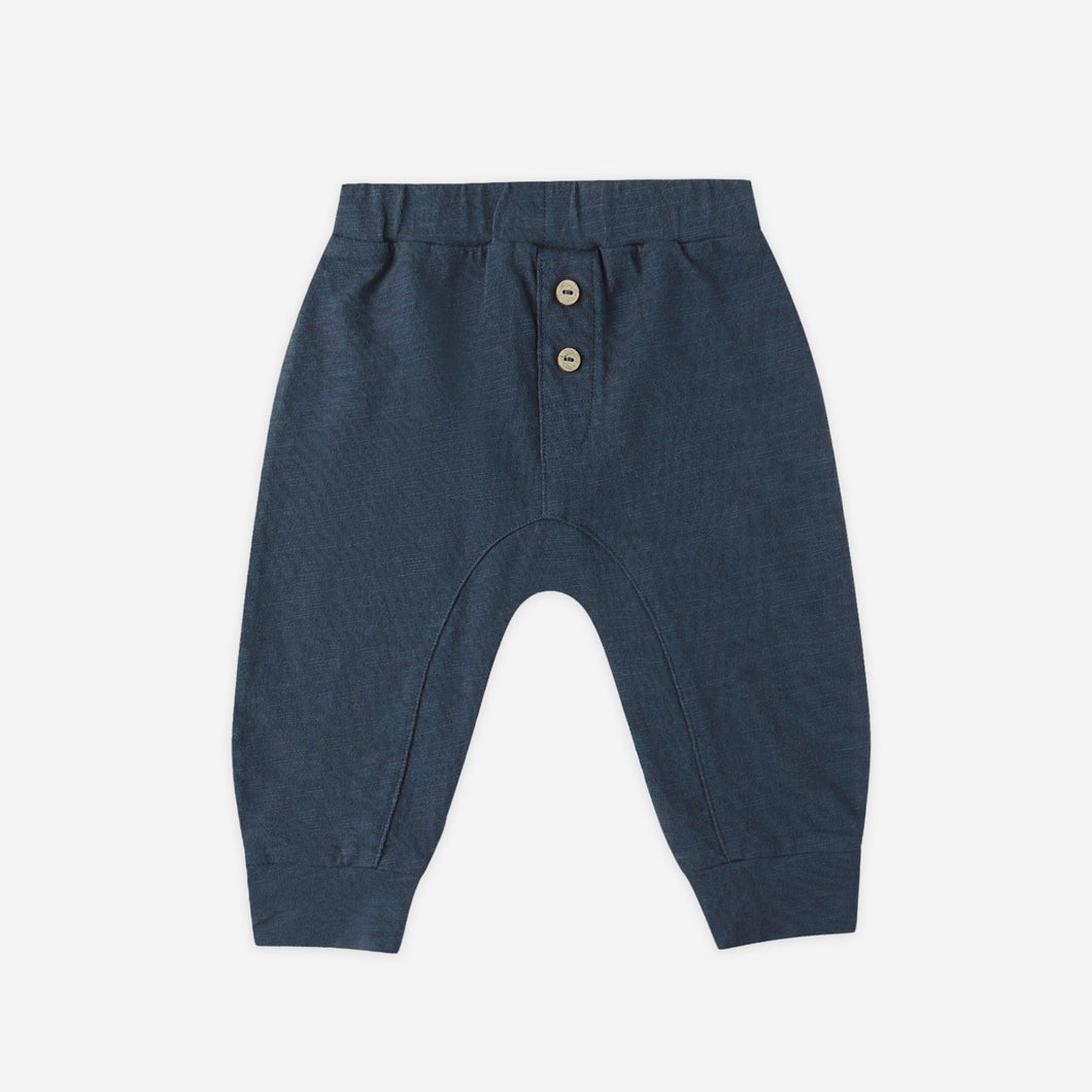 Navy blue baby pants with button details on a white background