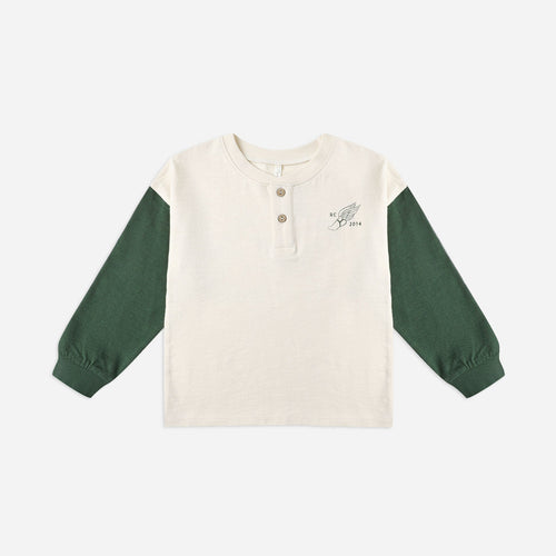 Long-sleeve shirt with green sleeves and a white body on a light beige background