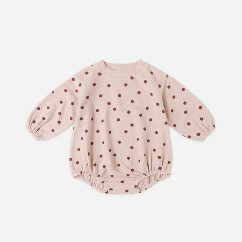 Pink baby romper with red polka dots on a white background