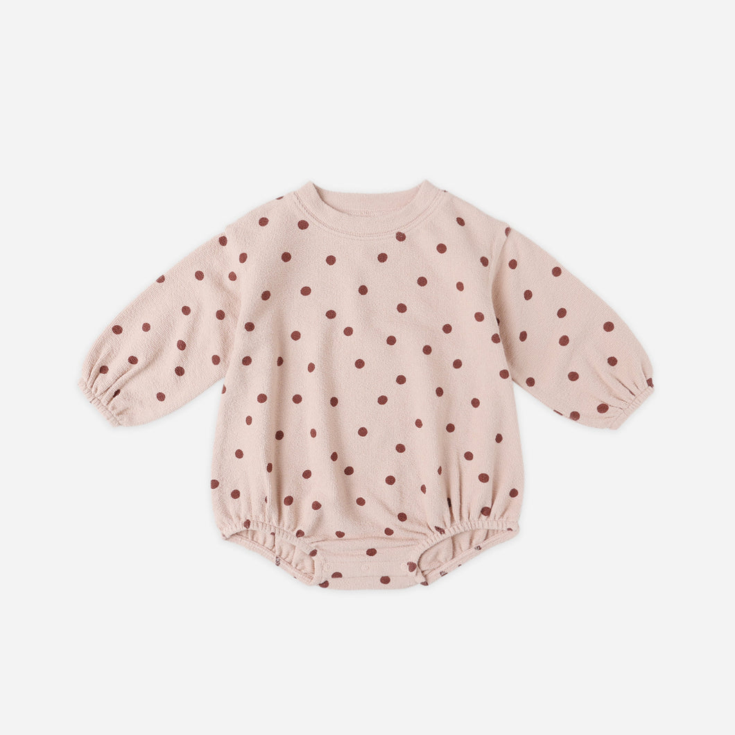Pink baby romper with red polka dots on a white background