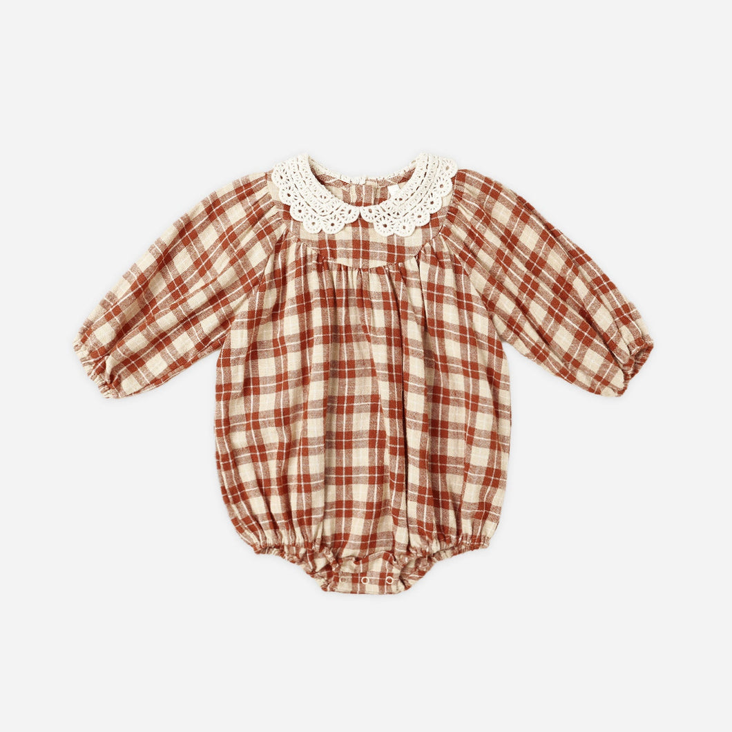 Red and white checkered baby romper with lace collar on a light beige background