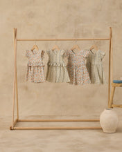 Load image into Gallery viewer, Rylee+Cru Brielle Blue Floral Dress hanging on a rack, showcasing its vibrant floral pattern and lightweight fabric.