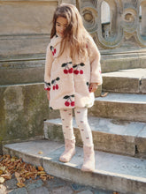 Load image into Gallery viewer, Young girl in a cherry-patterned coat standing on stone steps outdoors.