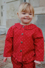 Load image into Gallery viewer, Child wearing a red polka dot outfit standing outdoors.