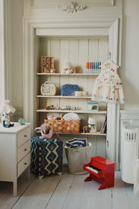 Children's room with shelves, toys, and a red toy piano.