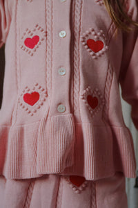 Pink cardigan with heart patterns on a blurred background