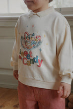 Load image into Gallery viewer, Child wearing a cream sweatshirt with colorful text and graphics, standing indoors.