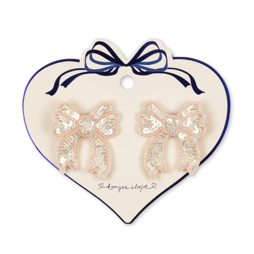Heart-shaped card with bow-shaped earrings on a white background