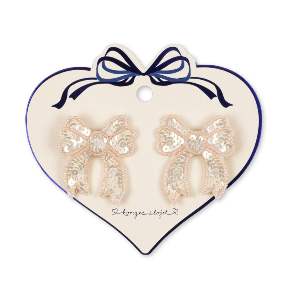 Heart-shaped card with bow-shaped earrings on a white background