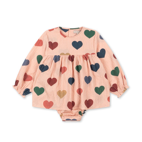 Children's outfit with a pink background and colorful heart patterns on a white background